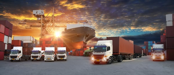 Cargo vessel and trucks at sunset