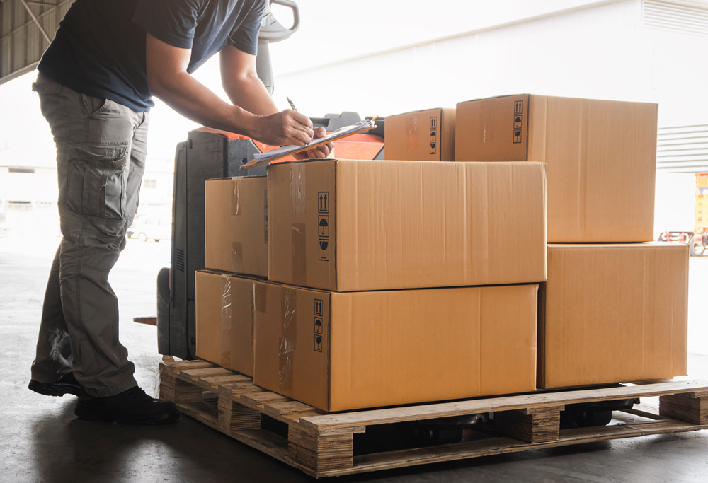 Operario revisando un pedido de comercio electrónico sobre un pallet de cajas
